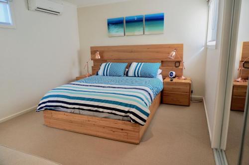 a bedroom with a wooden bed with a striped blanket at Beachcomber in Point Lonsdale