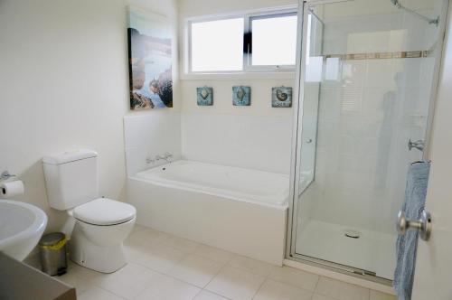 a white bathroom with a shower and a toilet at Beachcomber in Point Lonsdale