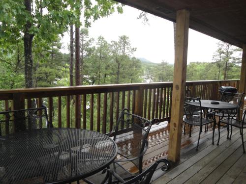 a porch with tables and chairs on a deck with a view at C7, Three bedroom, three bath log-sided, luxury Harbor North cottage with hot tub cottage in Mount Ida