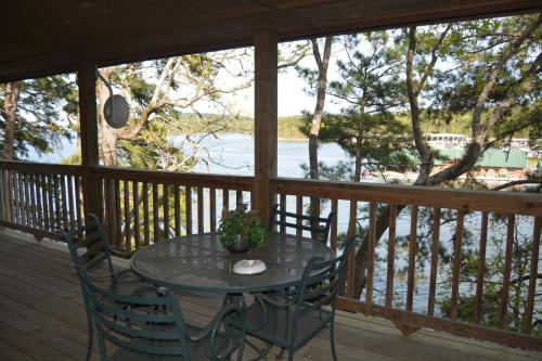 una mesa y sillas en un porche con vistas al agua en C14, Two bedroom, two bath, log-sided, luxury Harbor North cottage overlooking the lake, cottage, en Mount Ida
