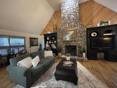 a living room with a couch and a stone fireplace at C19, One bedroom luxury, log-sided Couple's Cottage with private hot tub and unique extras cottage in Mount Ida
