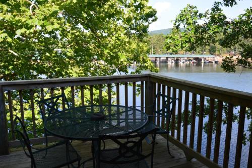uma mesa e cadeiras numa varanda com vista para um rio em C10, Two bedroom, two bath log-sided, lake view, luxury Harbor North cottage with hot tub cottage em Mount Ida