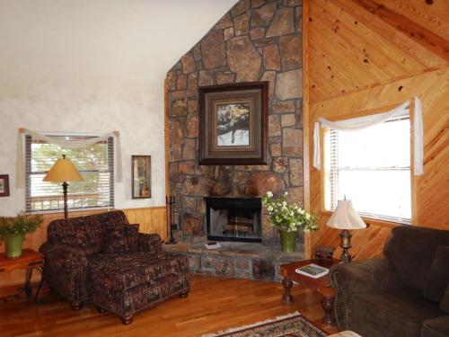 a living room with a stone fireplace in a house at Luxury, loft, log-sided two bedroom Harbor North cottage cottage in Mount Ida
