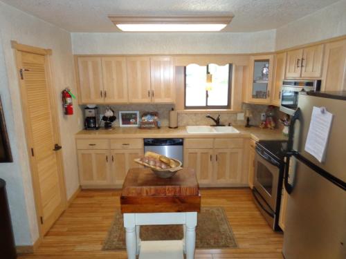 una cocina con armarios de madera y un bol de fruta en una mesa en C23, Two bedroom, two bath log-sided, luxury Harbor North cottage with hot tub cottage, en Mount Ida