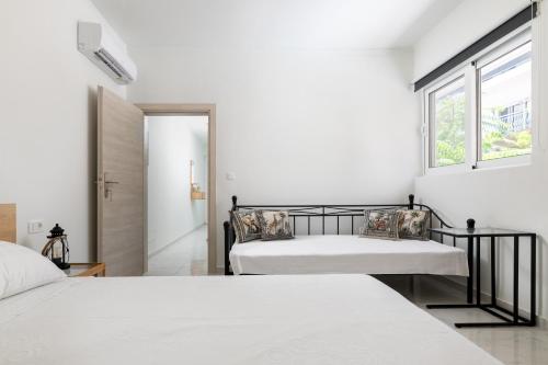 two beds in a white room with a window at Άνετο διαμέρισμα με κήπο in Rhodes Town