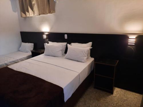 um quarto de hotel com duas camas com almofadas brancas em GH Hotel Express em Juiz de Fora