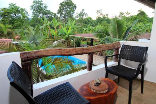 a balcony with two chairs and a table and a pool at Natura Gardens Galápagos in Bellavista