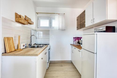 a kitchen with white cabinets and a white refrigerator at Apartments by the sea Grebastica, Sibenik - 11463 in Grebaštica