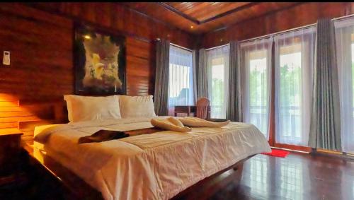 Schlafzimmer mit einem Bett mit weißer Bettwäsche und Fenstern in der Unterkunft Coriana Dive Resort in Waisai
