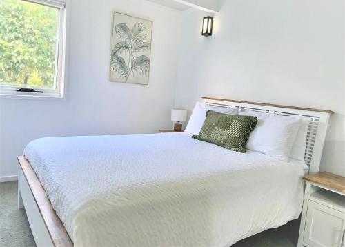 a white bedroom with a white bed and a window at Pandanus Pocket 3BR Beachside Condo by uHoliday in Casuarina
