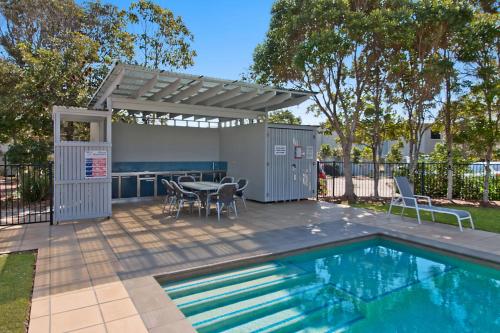 a patio with a table and chairs next to a swimming pool at Pandanus Pocket 3BR Beachside Condo by uHoliday in Casuarina