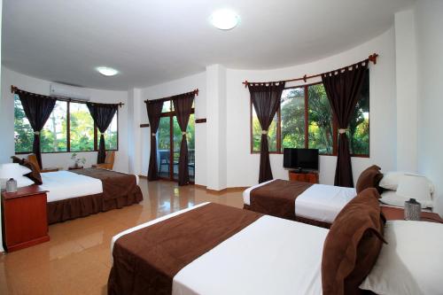 a hotel room with two beds and a television at Natura Gardens Galápagos in Bellavista