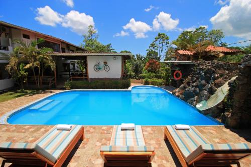 a swimming pool with two chairs and a house at Natura Gardens Galápagos in Bellavista