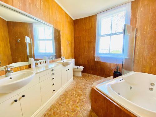 a bathroom with two sinks and a tub and a toilet at The Esplanade Hotel in Auckland