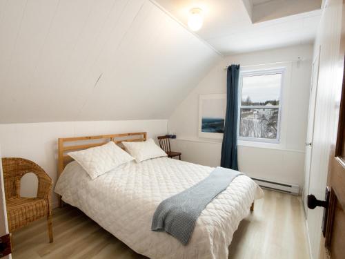Schlafzimmer mit einem Bett und einem Fenster in der Unterkunft Les Chalets Tourisma - Maison de campagne avec spa privé - La Familiale in Saint-Raymond