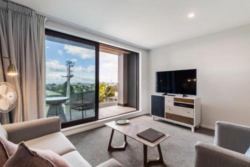 a living room with a tv and a large window at FERNZ Motel & Apartments Birkenhead in Auckland
