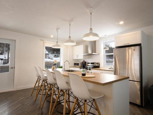 a kitchen with a table and chairs and a refrigerator at Les Chalets Tourisma - Maison de campagne avec spa privé - La Familiale in Saint-Raymond