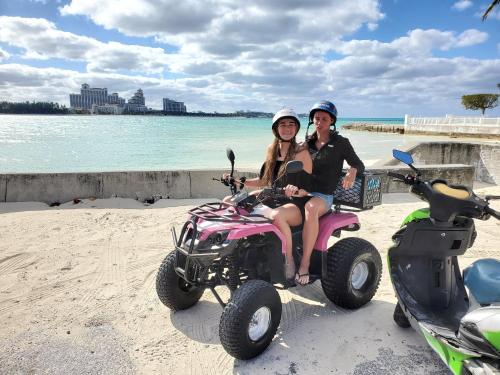 a man and woman sitting on a four wheeler on the beach at Da Pink And White Palace in Nassau