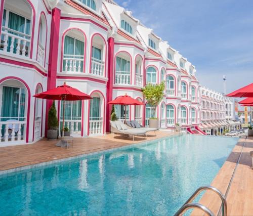 a swimming pool in front of a pink building at Hotel Midtown Ratsada in Phuket Town