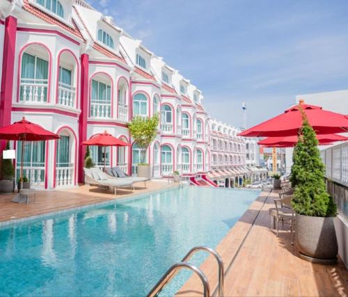 a swimming pool in front of a pink building at Hotel Midtown Ratsada in Phuket Town