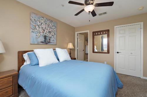 a bedroom with a blue bed with a ceiling fan at Cozy Top Floor 2BR Condo with View and Amenities!! in Branson