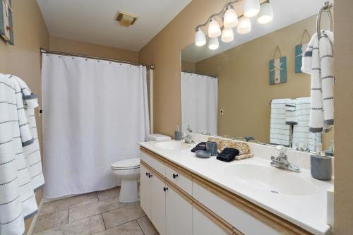 ein Badezimmer mit einem Waschbecken, einem WC und einem Spiegel in der Unterkunft Cozy Top Floor 2BR Condo with View and Amenities!! in Branson