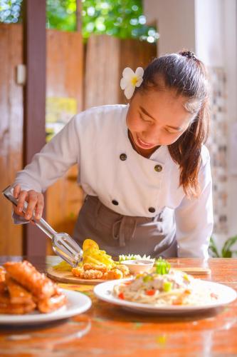 a woman in a kitchen preparing food on a table at Natura Vista in Panglao