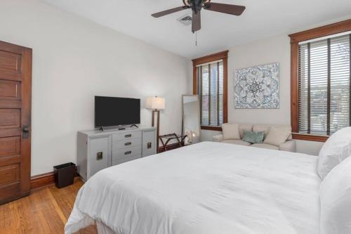een witte slaapkamer met een groot bed en een flatscreen-tv bij The Heights Hideaway a Stylish & Spacious Retreat in Tower Grove