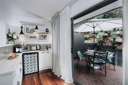 a kitchen and dining room with a table and an umbrella at Palm House - by Coast Hosting in Terrigal