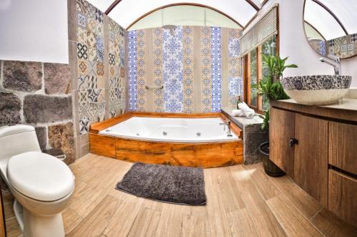 a bathroom with a tub and a toilet and a sink at Hotel Campestre La Periquera in Villa de Leyva