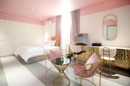 una camera d'albergo con letto, sedie e specchio di Baba Hotel Gimcheon a Gimcheon