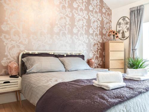1 dormitorio con 1 cama con papel de damasco en Afan Adventure, en Cymmer