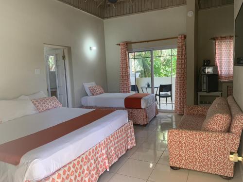 a bedroom with two beds and chairs and a table at King Suite at Oceanview Resort in Jamaica - Enjoy 7 miles of White Sand Beach! in Negril