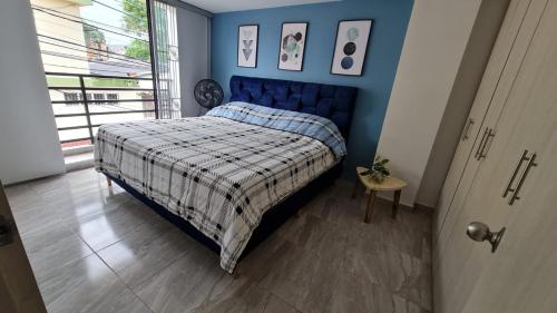 1 dormitorio con 1 cama con pared azul en Hermoso Apartamento Entero - Parqueadero - Ibague - Roble en Ibagué