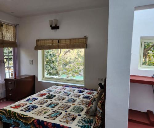 a bedroom with a bed with a quilt on it at Samira's Birds & Butterflies Park-Spashram Ganga Beach Retreat in Rishīkesh