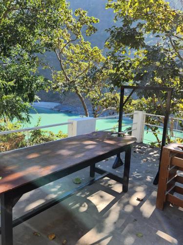 a wooden picnic table with a view of the water at Samira's Birds & Butterflies Park-Spashram Ganga Beach Retreat in Rishīkesh