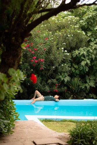a woman laying in a swimming pool in a garden at Refugio de Piedras in Ciudad Lujan de Cuyo