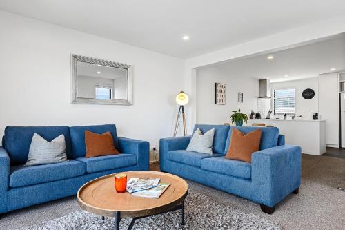 a living room with two blue couches and a table at 2 Bedroom City Pad with Free Car Park in Christchurch