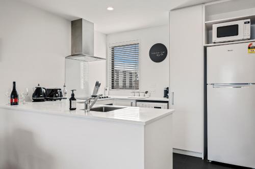 a white kitchen with a sink and a refrigerator at 2 Bedroom City Pad with Free Car Park in Christchurch