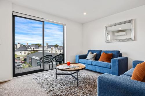 a living room with a blue couch and a table at 2 Bedroom City Pad with Free Car Park in Christchurch