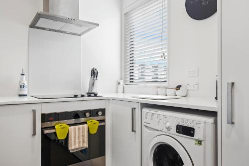 a white kitchen with a washer and dryer at 2 Bedroom City Pad with Free Car Park in Christchurch