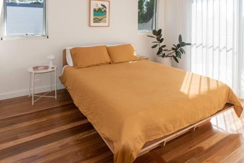 a bedroom with a bed with a yellow blanket on it at The Loft @ Mollymook 70s Beach House in Mollymook