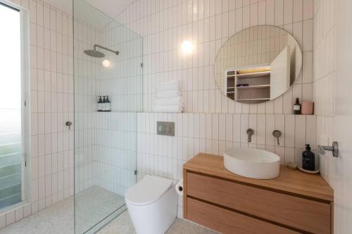 a bathroom with a toilet and a sink and a mirror at The Loft @ Mollymook 70s Beach House in Mollymook
