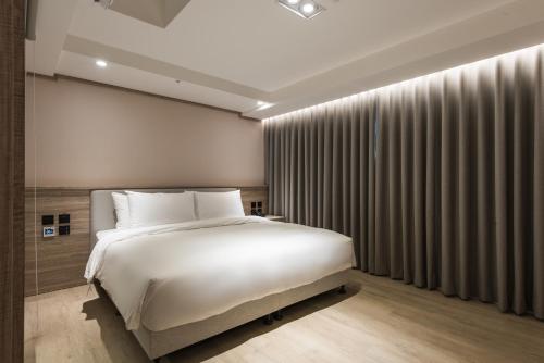 a bedroom with a large white bed and curtains at Spring Rhapsody Hotel in Taichung