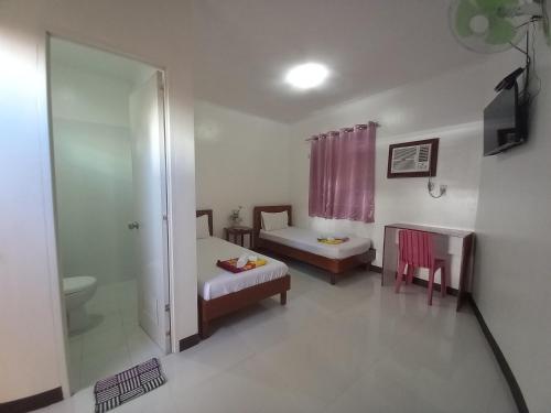 um quarto com duas camas e uma mesa e uma janela em Alinchlo Hotel em Legazpi