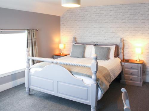 a bedroom with a white bed and two night stands at Townend Cottage in Aikton