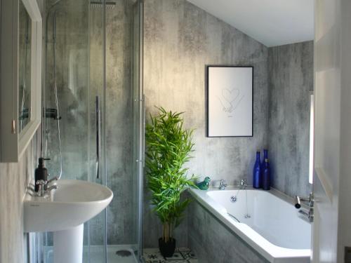 een badkamer met een wastafel, een bad en een douche bij Townend Cottage in Aikton