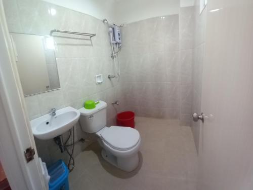 a bathroom with a white toilet and a sink at Alinchlo Hotel in Legazpi