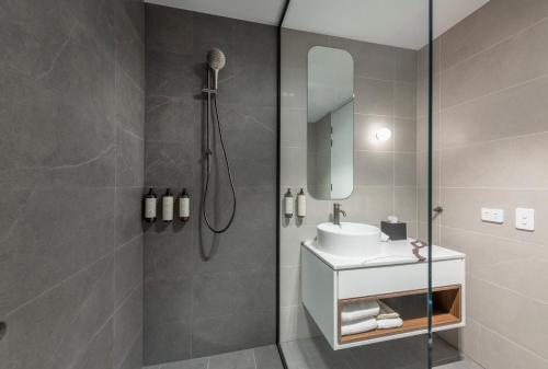 a bathroom with a shower with a sink and a mirror at TRYP by Wyndham Pulteney Street Adelaide in Adelaide