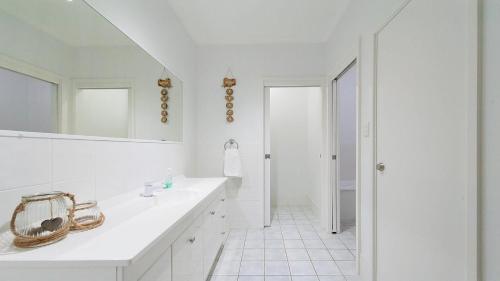 ein weißes Badezimmer mit einem Waschbecken und einem Spiegel in der Unterkunft Dutchie's Sand & Sea Beach House - easy walk to the beach in Nelson Bay